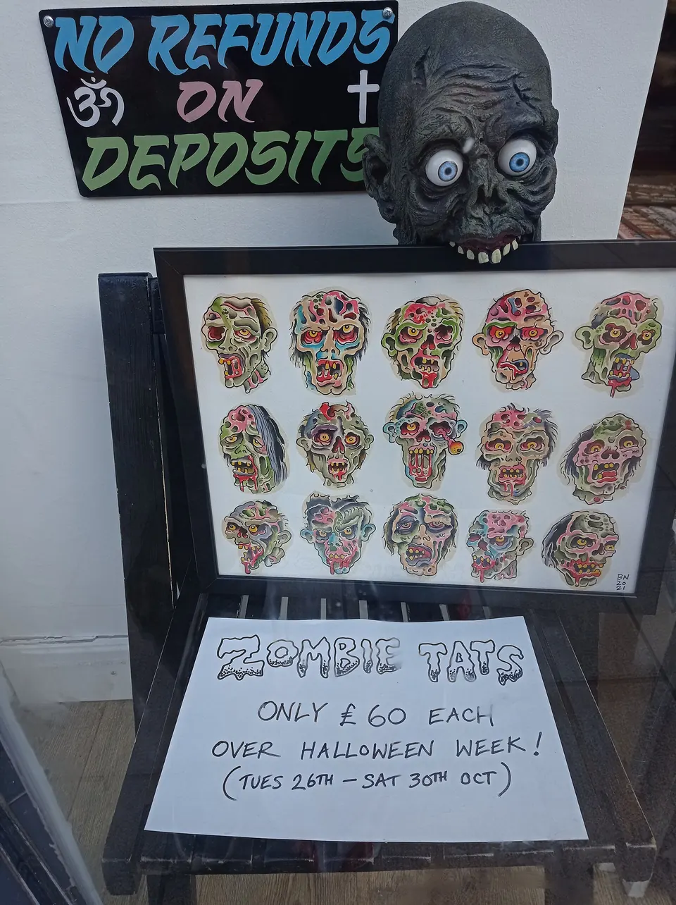 Halloween flash sheet of colorful zombie skull tattoos in a tattoo shop window with a fixed price for Halloween week