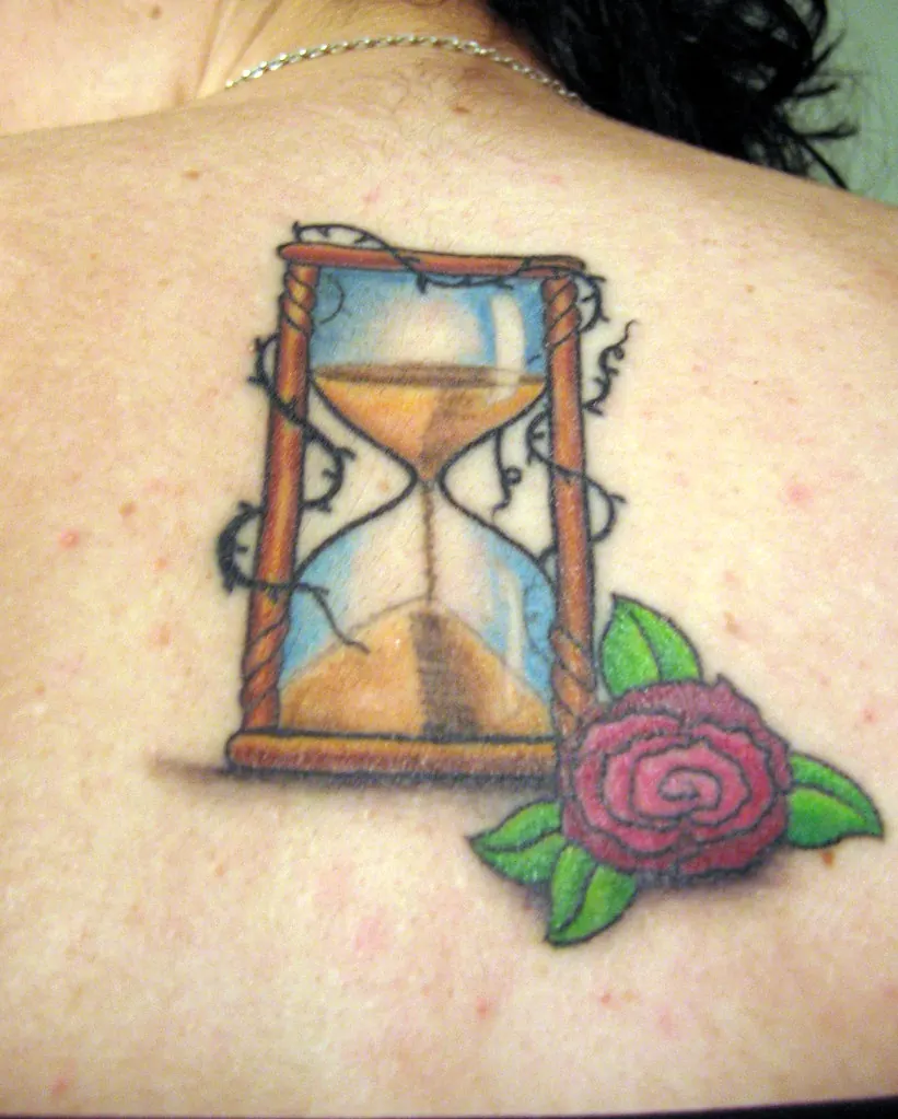 Hourglass with thorny vines and a red rose tattoo on the shoulder blade