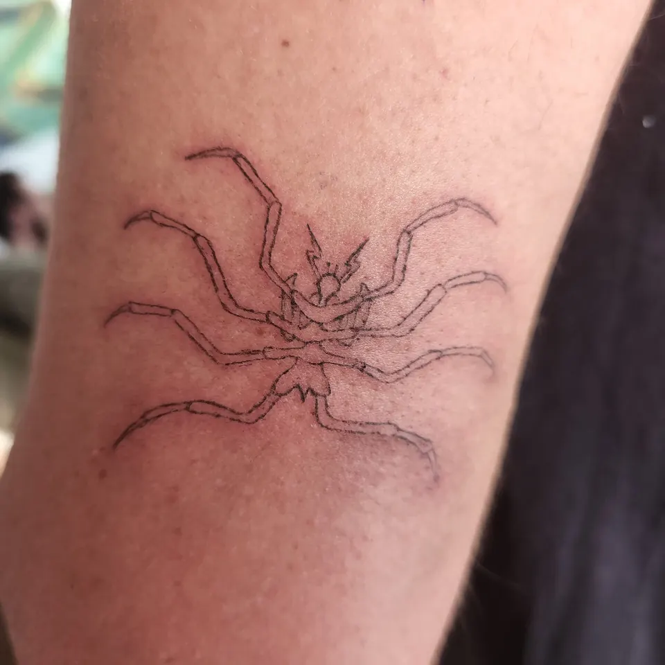 Fine-line sea spider tattoo on the arm