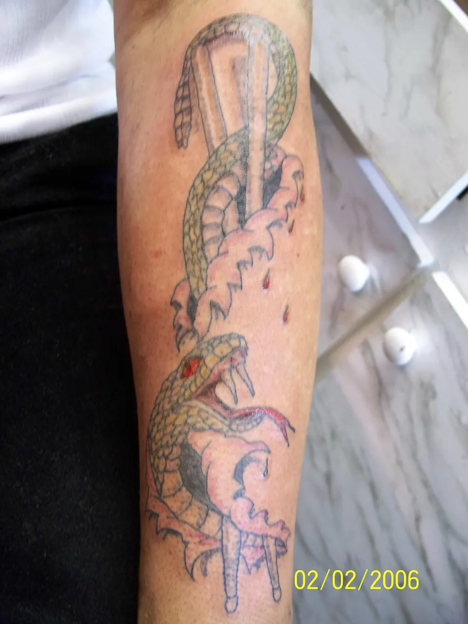 Snake coiled around drumsticks tattoo on the forearm