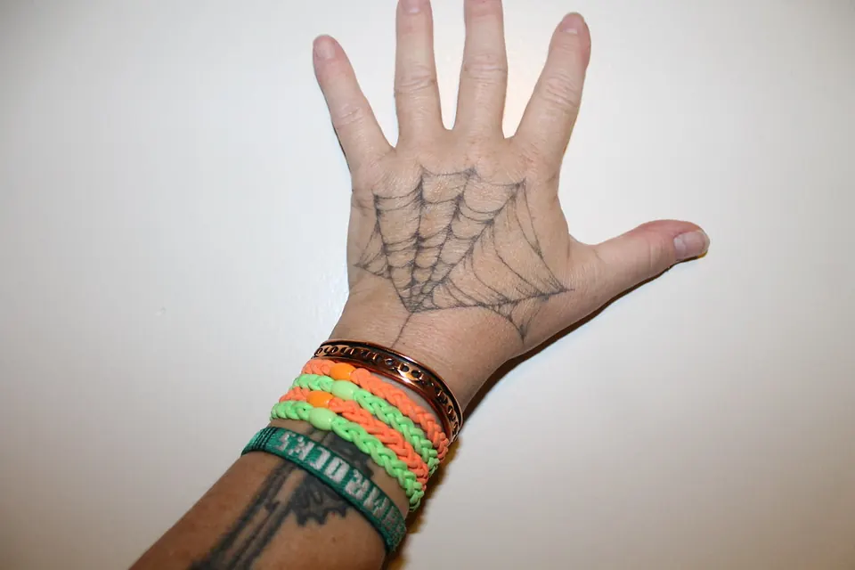 Fine spider web tattoo across the palm of the hand